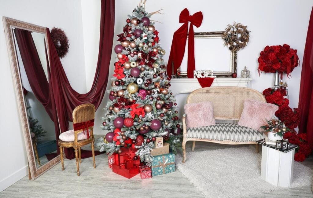 Christmas photography studio set in Vaughan with a flocked tree in burgundy and gold, deep wine velvet drapes, white mantel with NOEL lettering and a cane settee